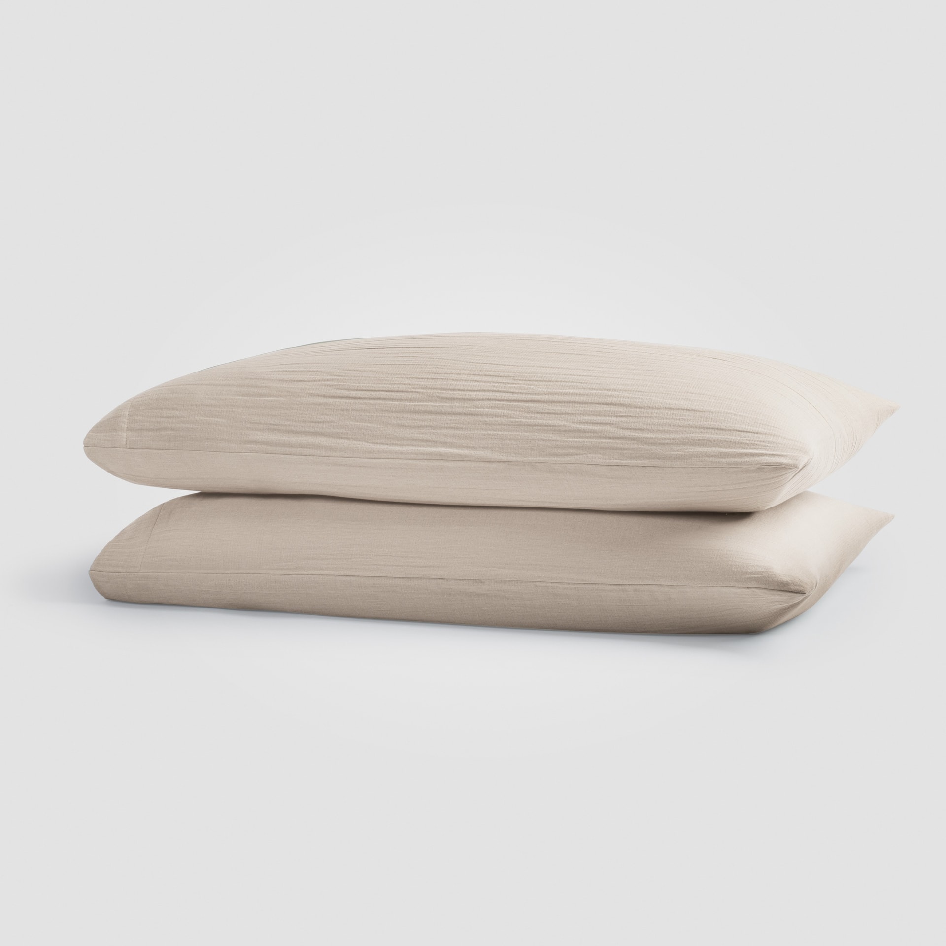 Beige pillowcases stacked on a plain white surface