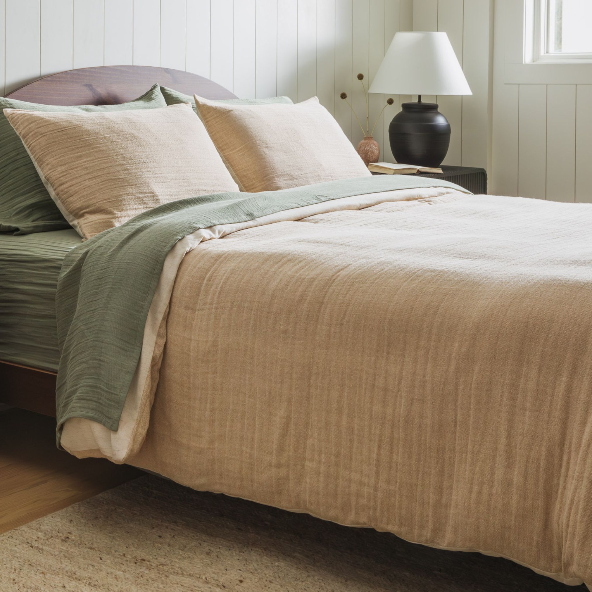 Beige bedding with white and rust pillows arranged against a neutral headboard