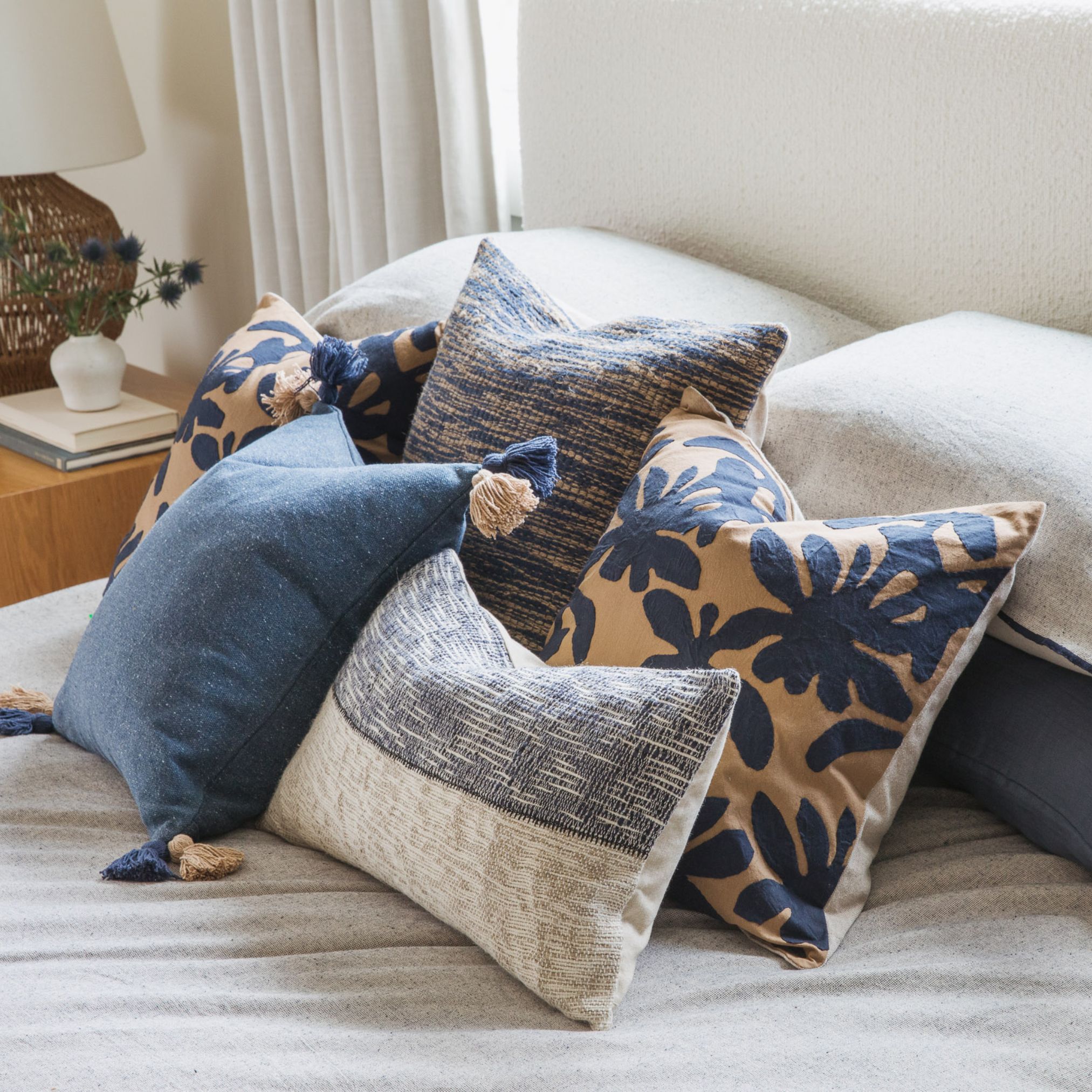 Bed with blue and beige pillows, a botanical-patterned pillow, and a striped duvet cover