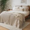 Bed with beige faux fur blanket, neutral pillows, and wood frame in a softly lit room
