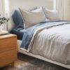 6 Blue and white bedding set with layered pillows next to a wooden nightstand