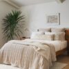 Bed with rust-colored bedding, white pillows, and a potted plant in the background