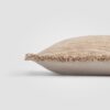 Side view of a beige pillow with visible woven texture and stitched edge