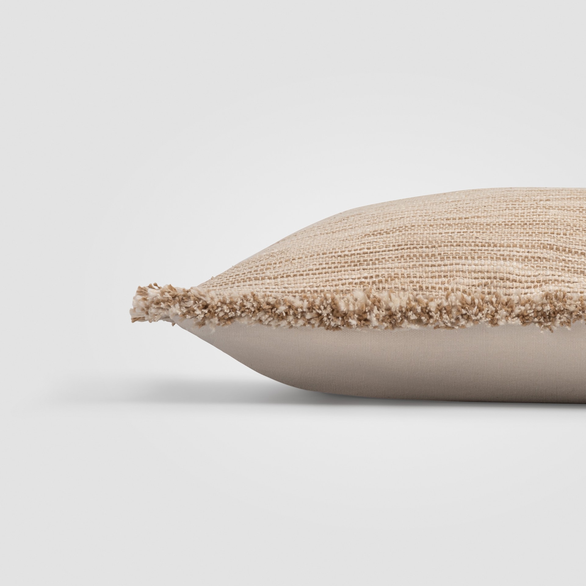 Side view of a beige pillow with visible woven texture and stitched edge