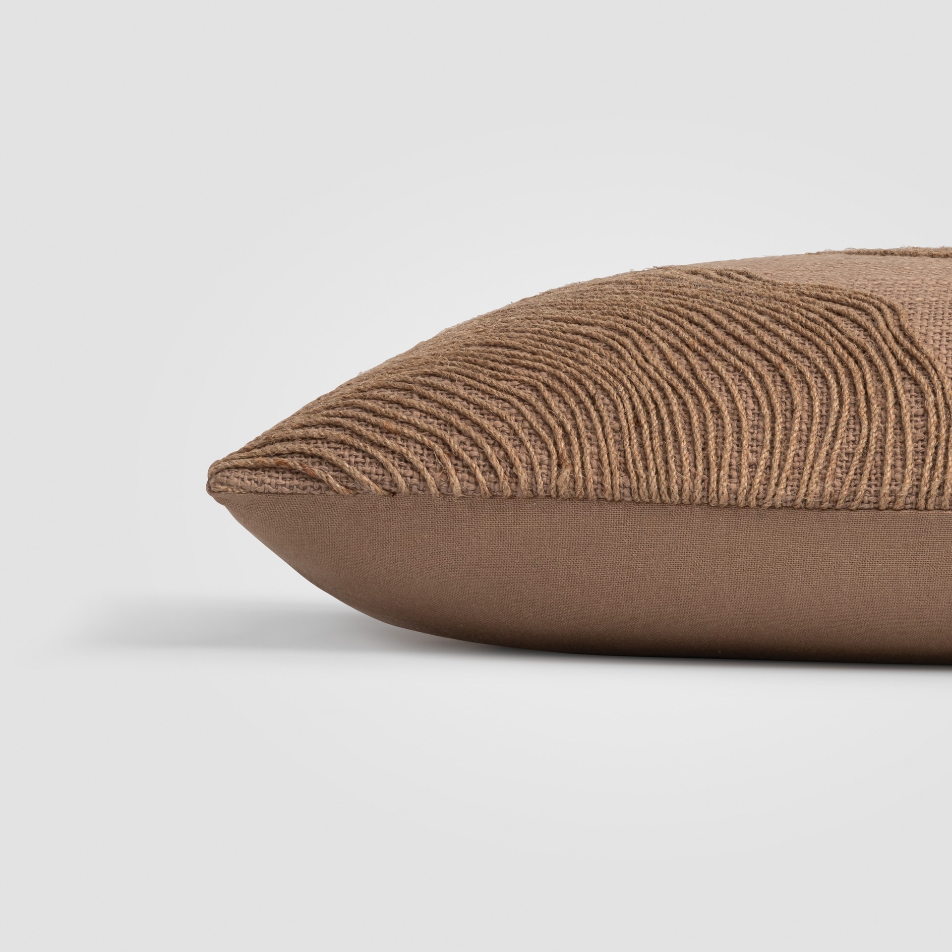 Side view of a beige pillow with visible woven texture and stitched edge