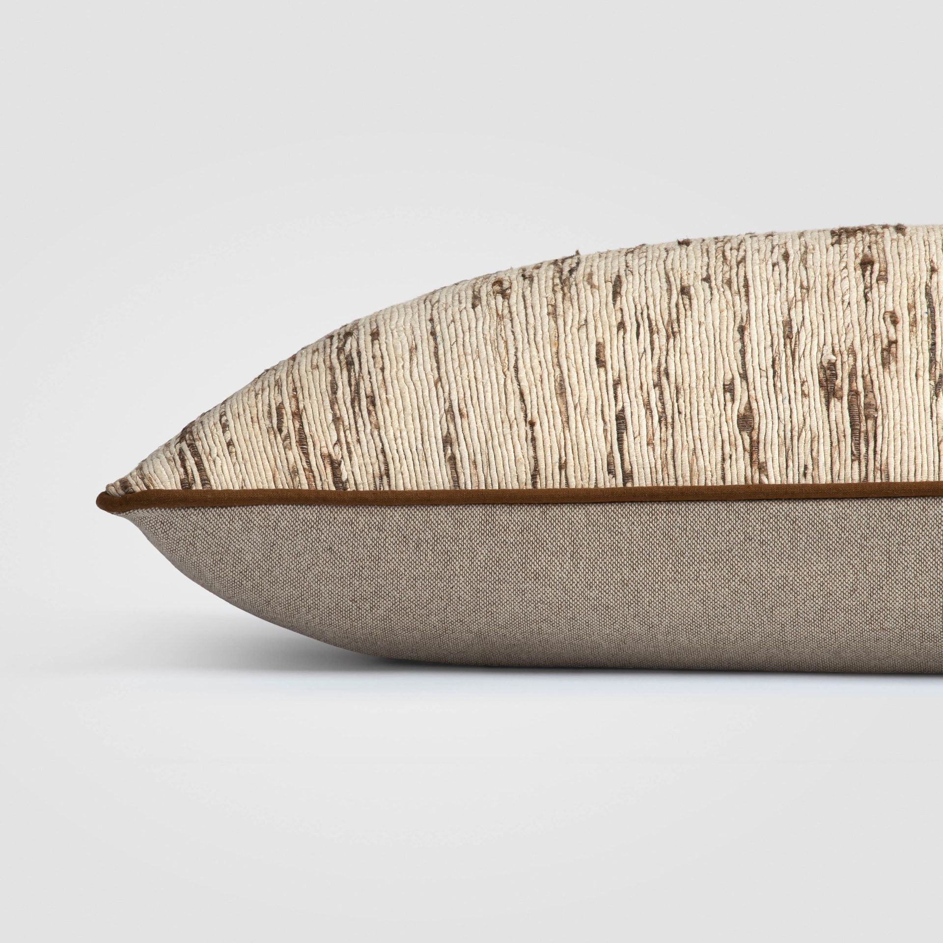 Side view of rectangular beige pillow with handwoven texture