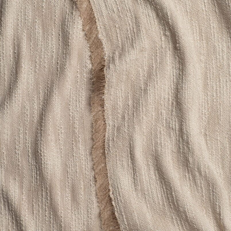 Close-up of beige cable knit fabric with soft, wavy texture