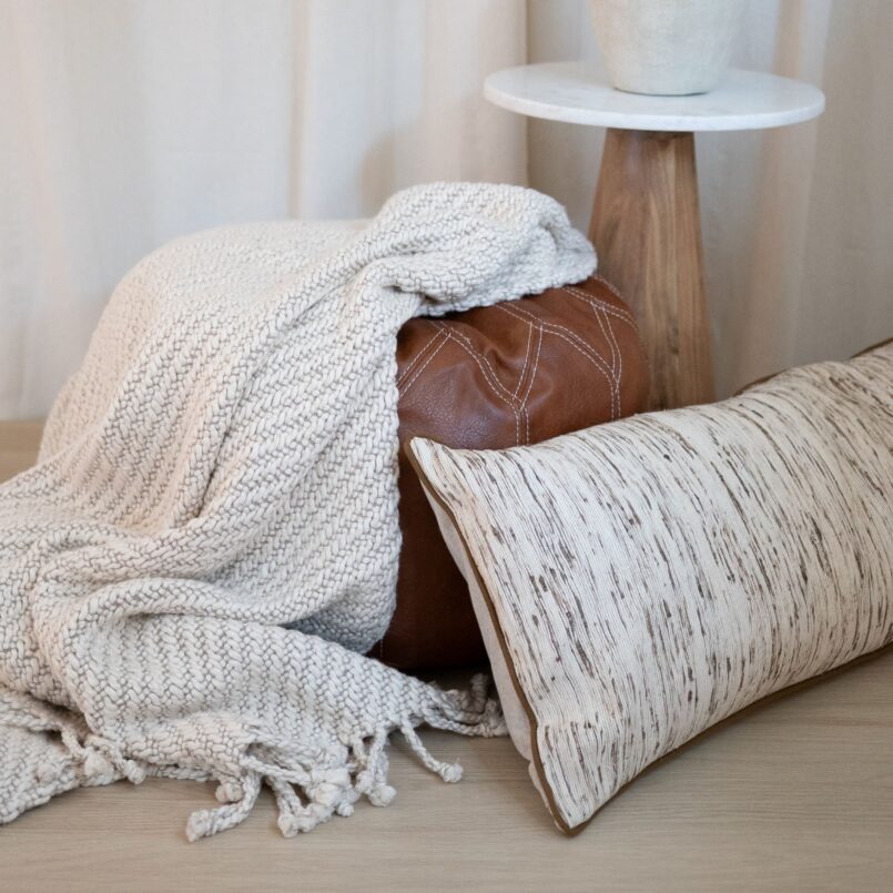 White bedding with textured pillows and a neutral throw blanket in a softly lit bedroom