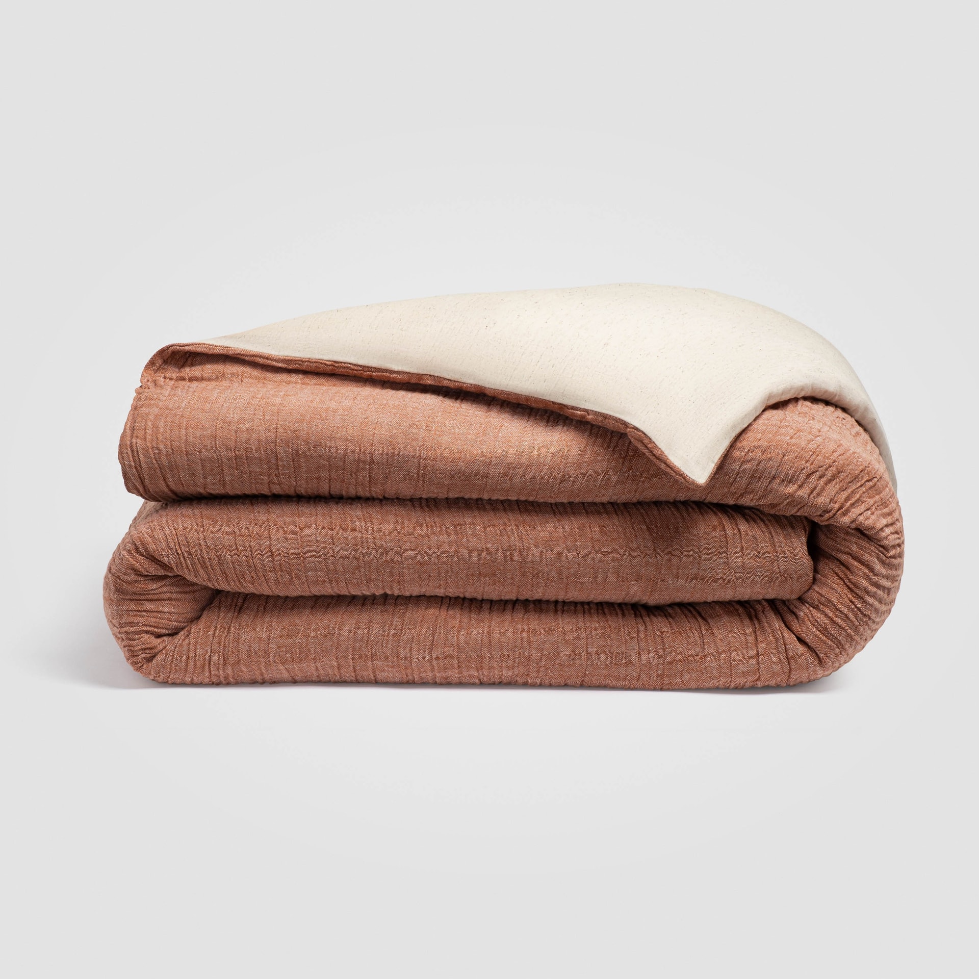Rolled rust-colored duvet cover displayed on a white background