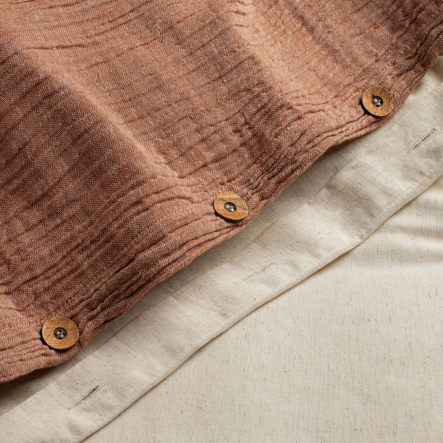 Close-up of rust-colored duvet cover with a visible weave and stitched seam