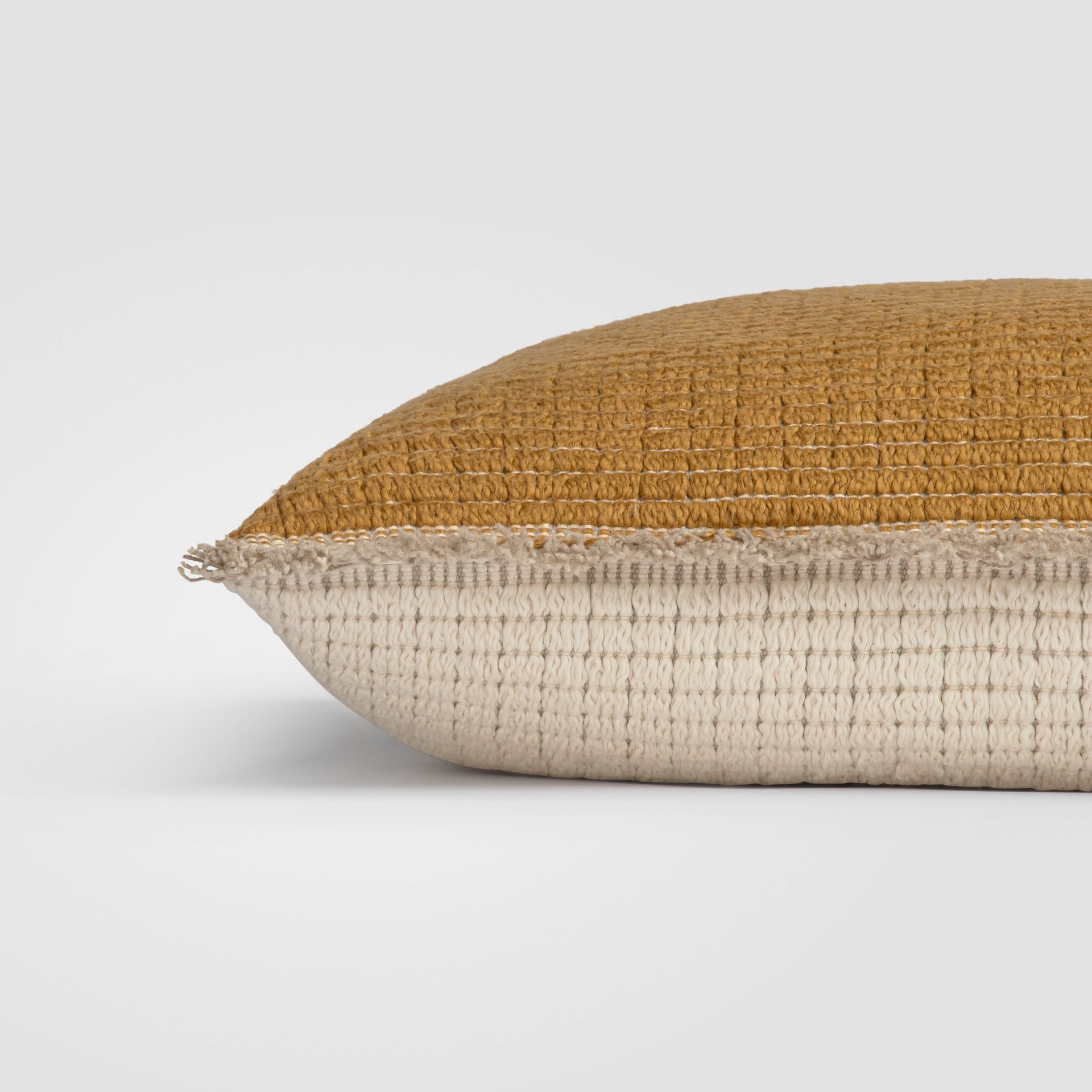 Side view of a golden yellow pillow with a smooth, velvety texture