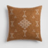 Burnt orange pillow with white tribal-inspired embroidered symbols