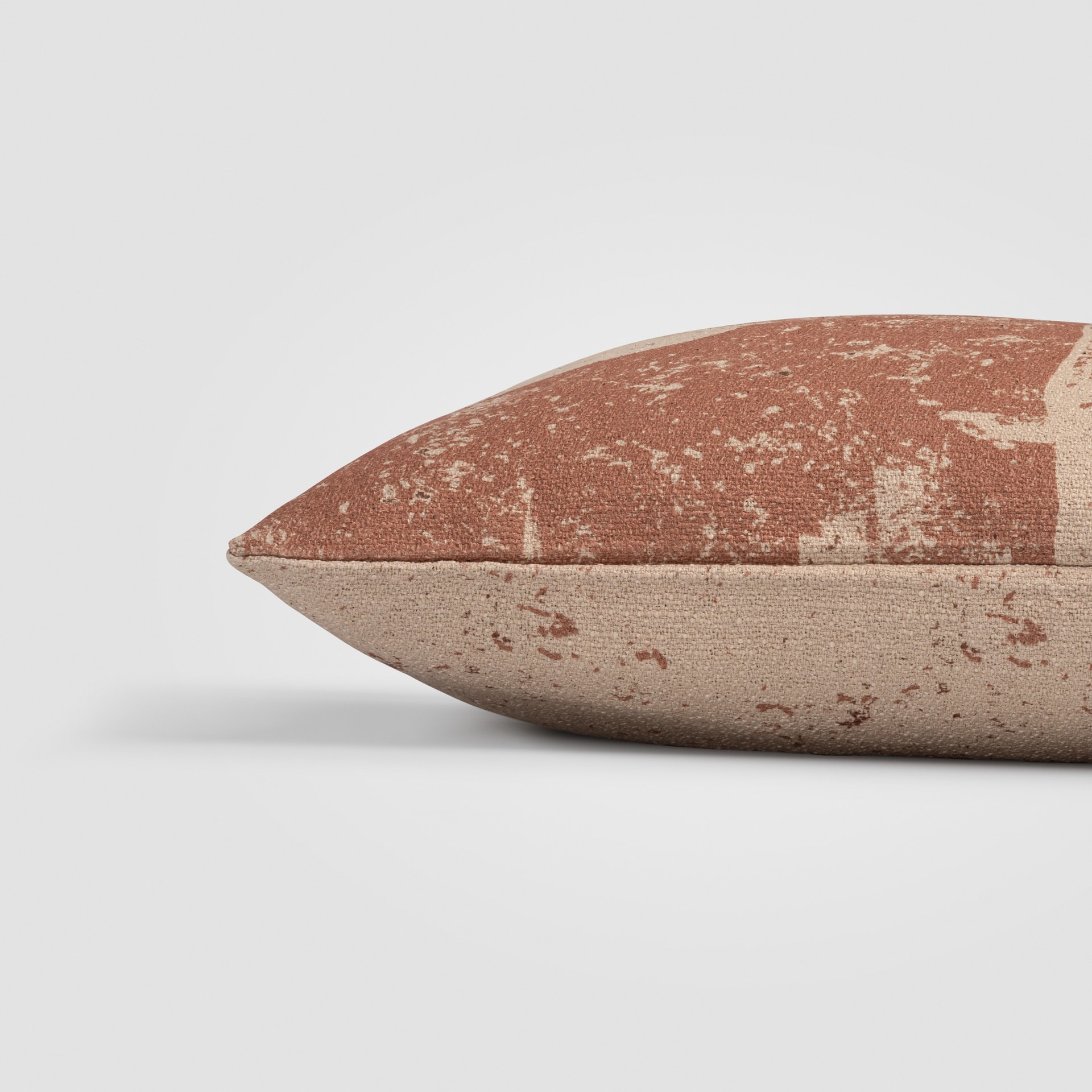 Side view of a rust and cream pillow with abstract geometric pattern