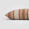 Side view of a rectangular rust pillow with cream and terracotta horizontal stripes