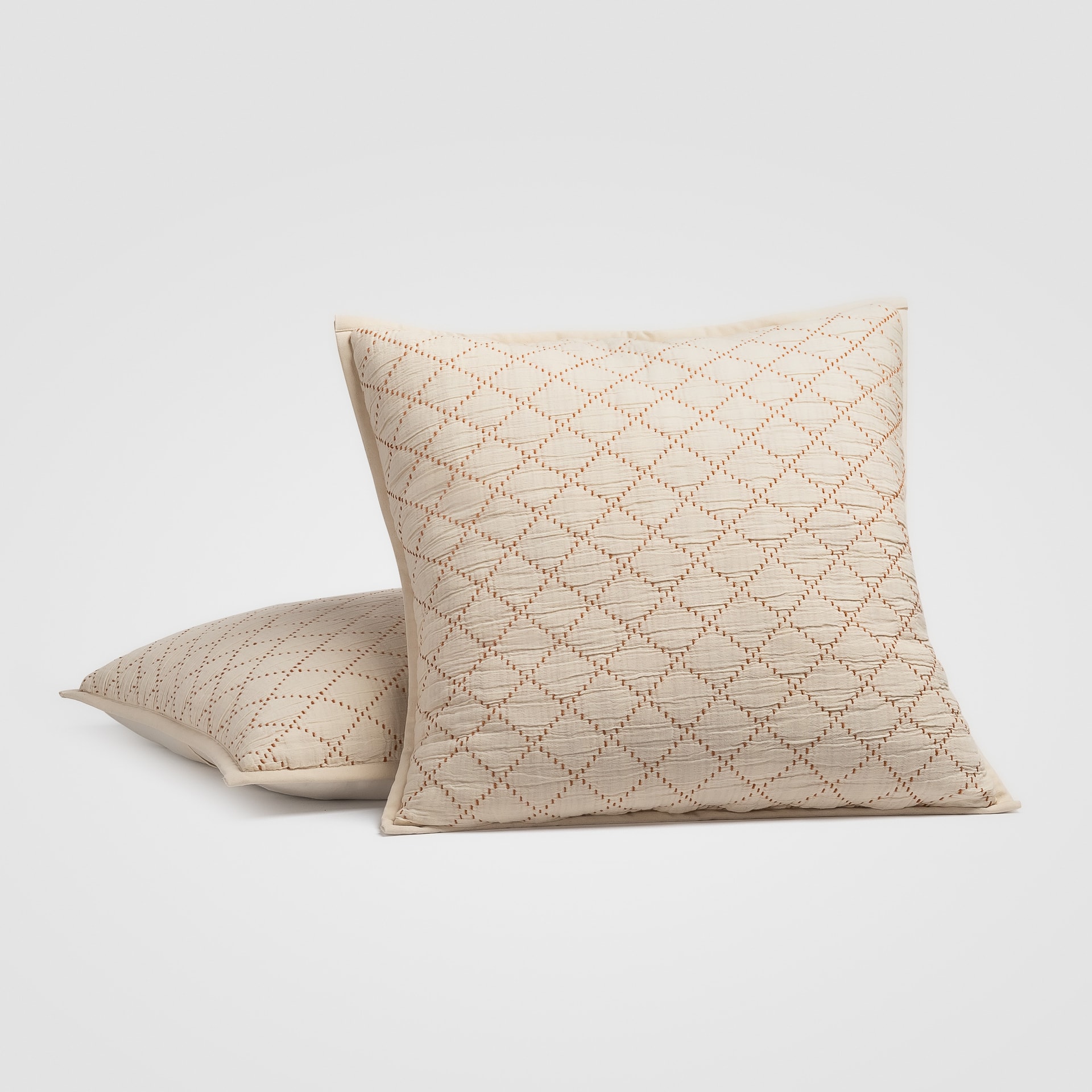 Decorative cream pillow with diamond pattern stitching on a white background
