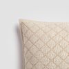 Close-up of cream pillow with textured diamond embroidery pattern