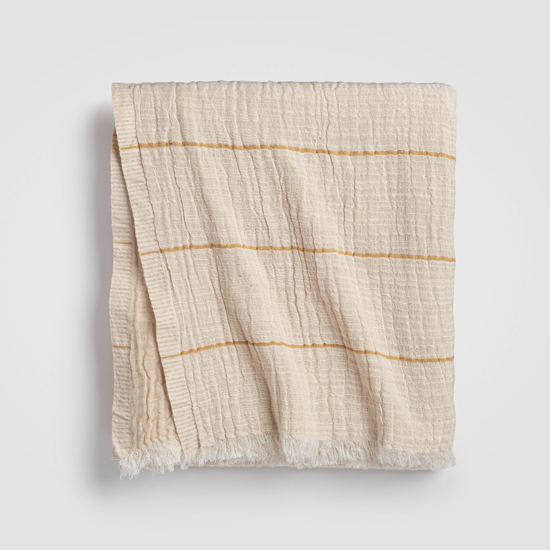 Folded beige knit throw blanket with textured stitching and soft drape