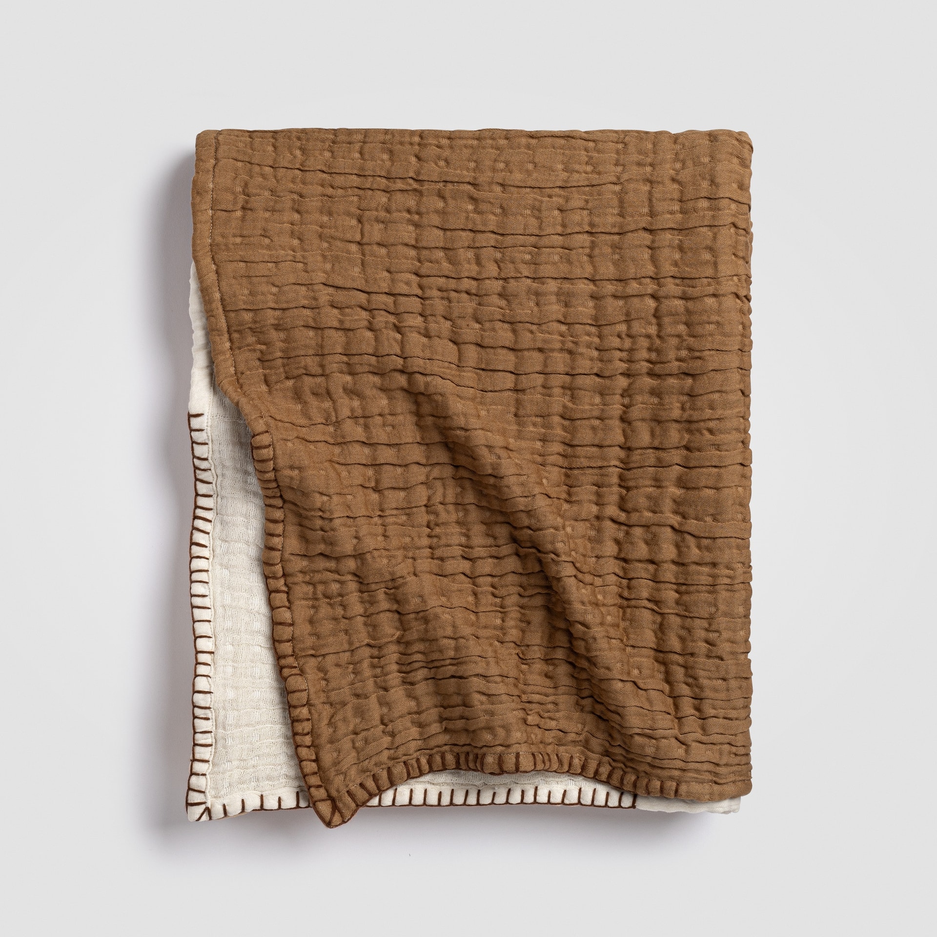 Folded rust-colored knit throw blanket with ribbed edge and soft texture