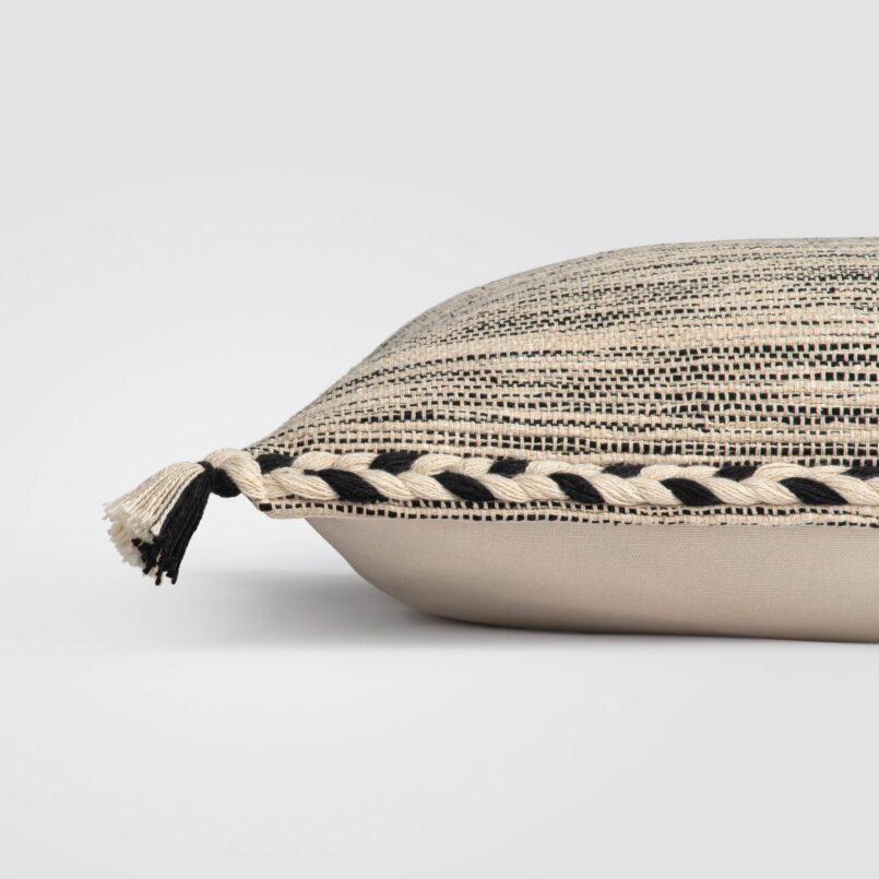 Folded rectangular pillow with a beige base and black stitched accents