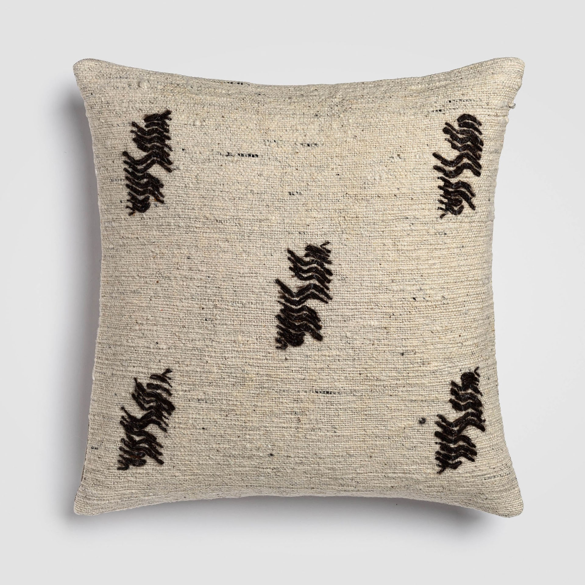 Light beige pillow with scattered dark embroidered floral designs