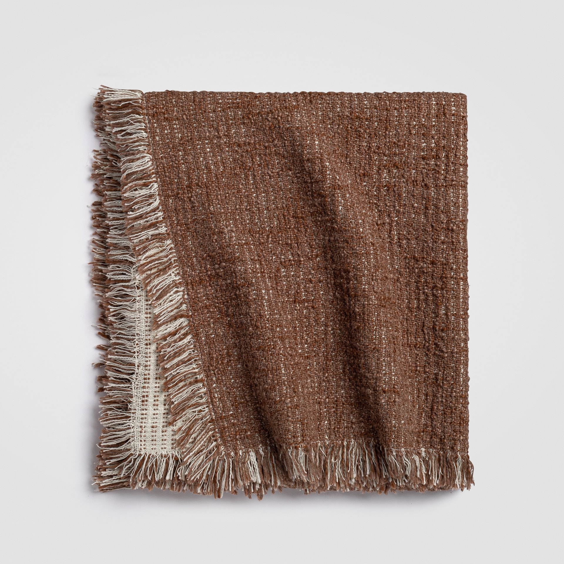 Folded rust knit throw blanket with thick braided knit pattern