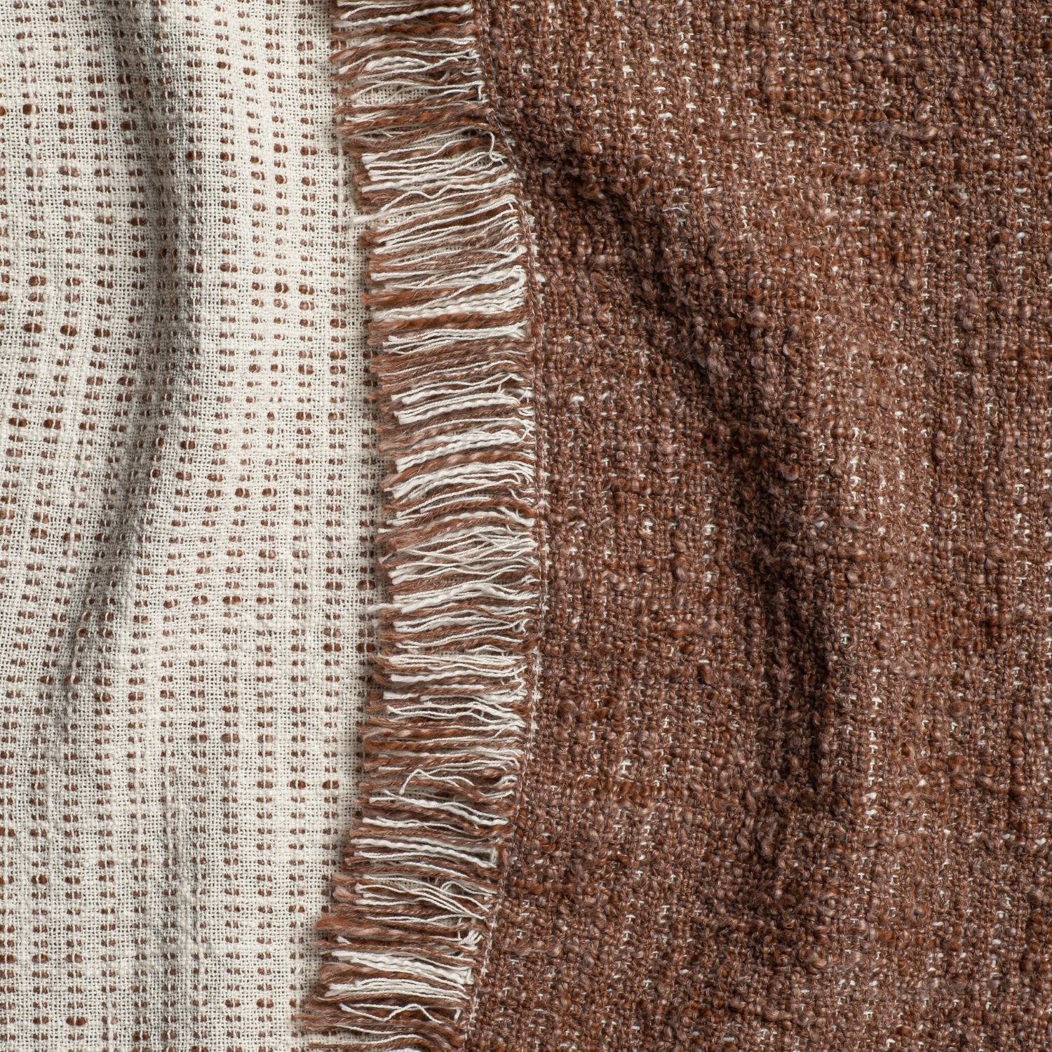 Beige and rust knit throw blankets stacked, showing detailed cable stitching