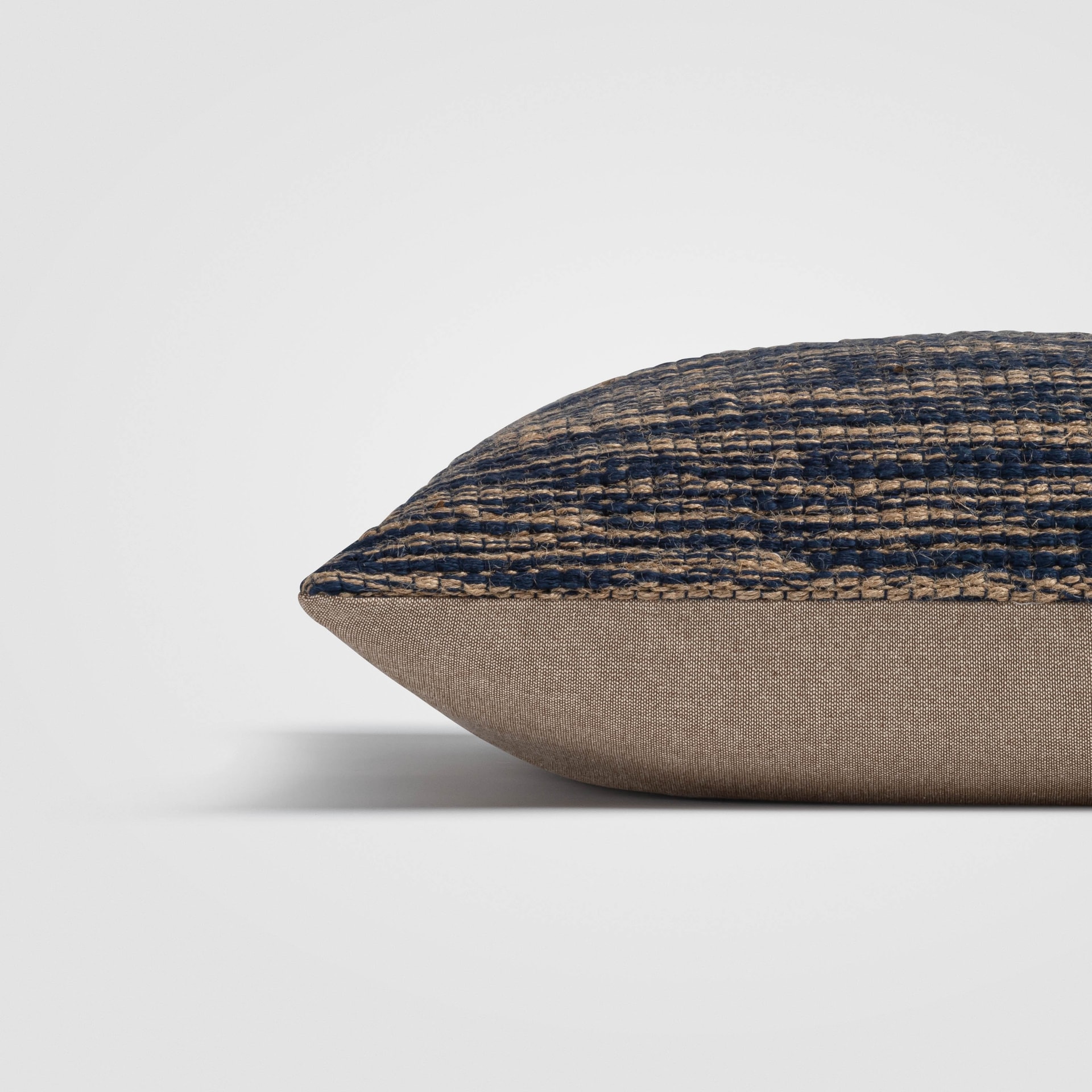 Side view of a black pillow with intricate woven beige pattern