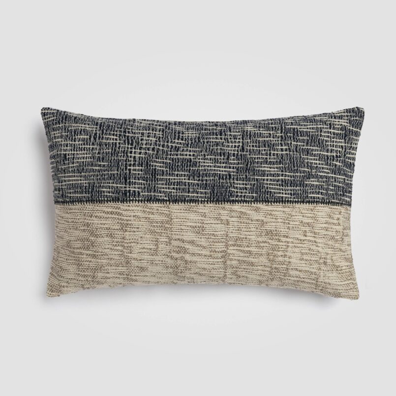Long rectangular pillow with geometric black and cream pattern and fringe trim