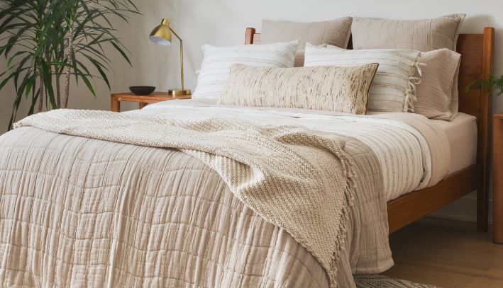 Cream bedding with textured pillows and soft lighting in a neutral bedroom