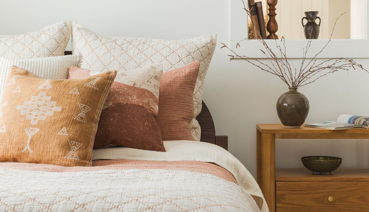 Light pink pillow with a rust-colored throw on a beige couch