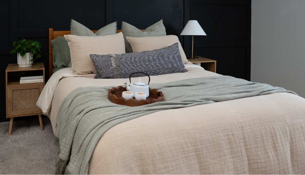 Light bedding with neutral pillows and a brown throw blanket in a modern bedroom