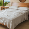Bed with white textured bedding, white pillows, and a light wood headboard
