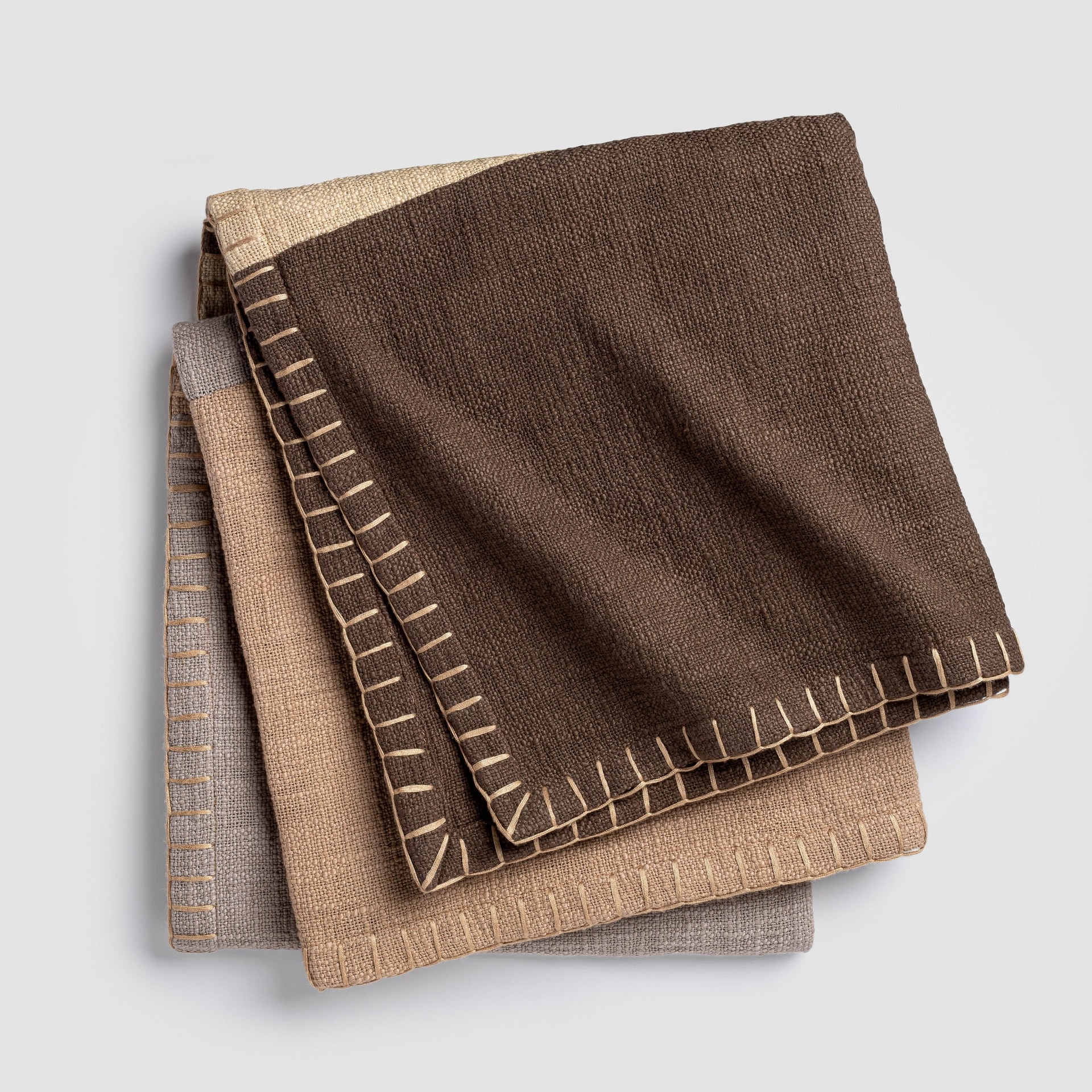 Three beige blankets folded on white background