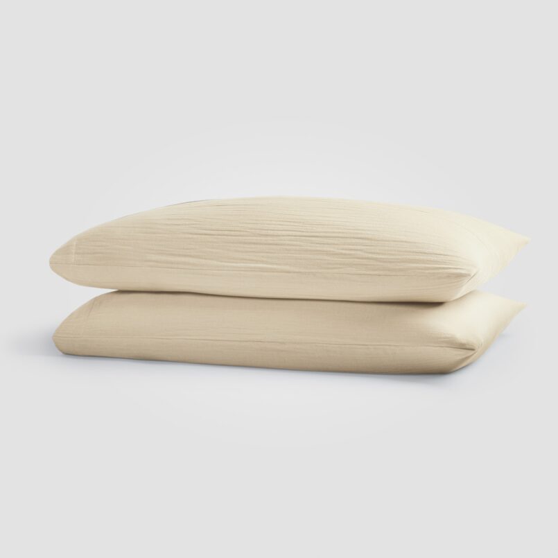 Beige pillowcases stacked on a plain white surface