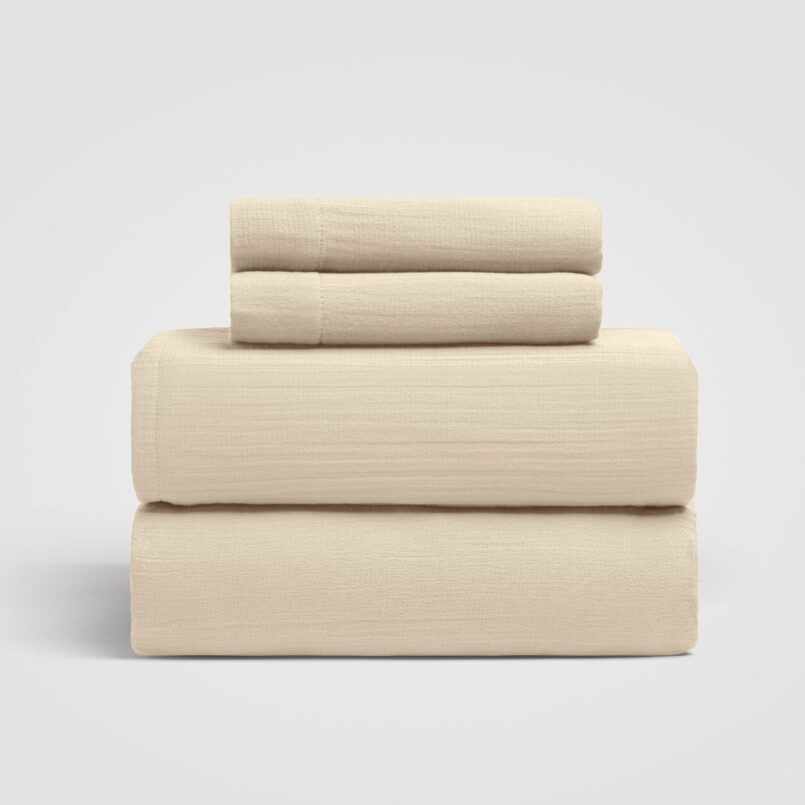 Set of three folded beige sheets stacked on a white background