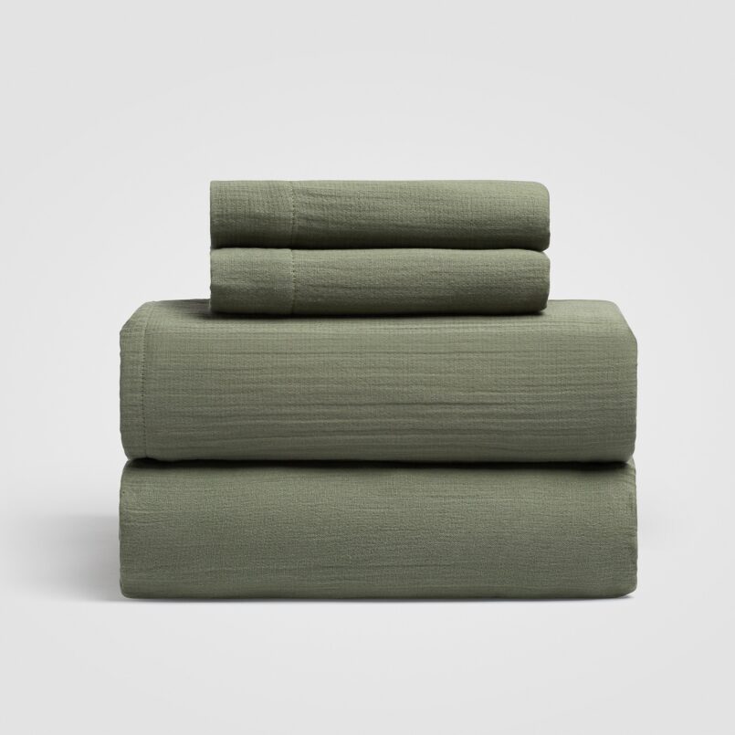 Set of three sage green sheet neatly stacked on a white background