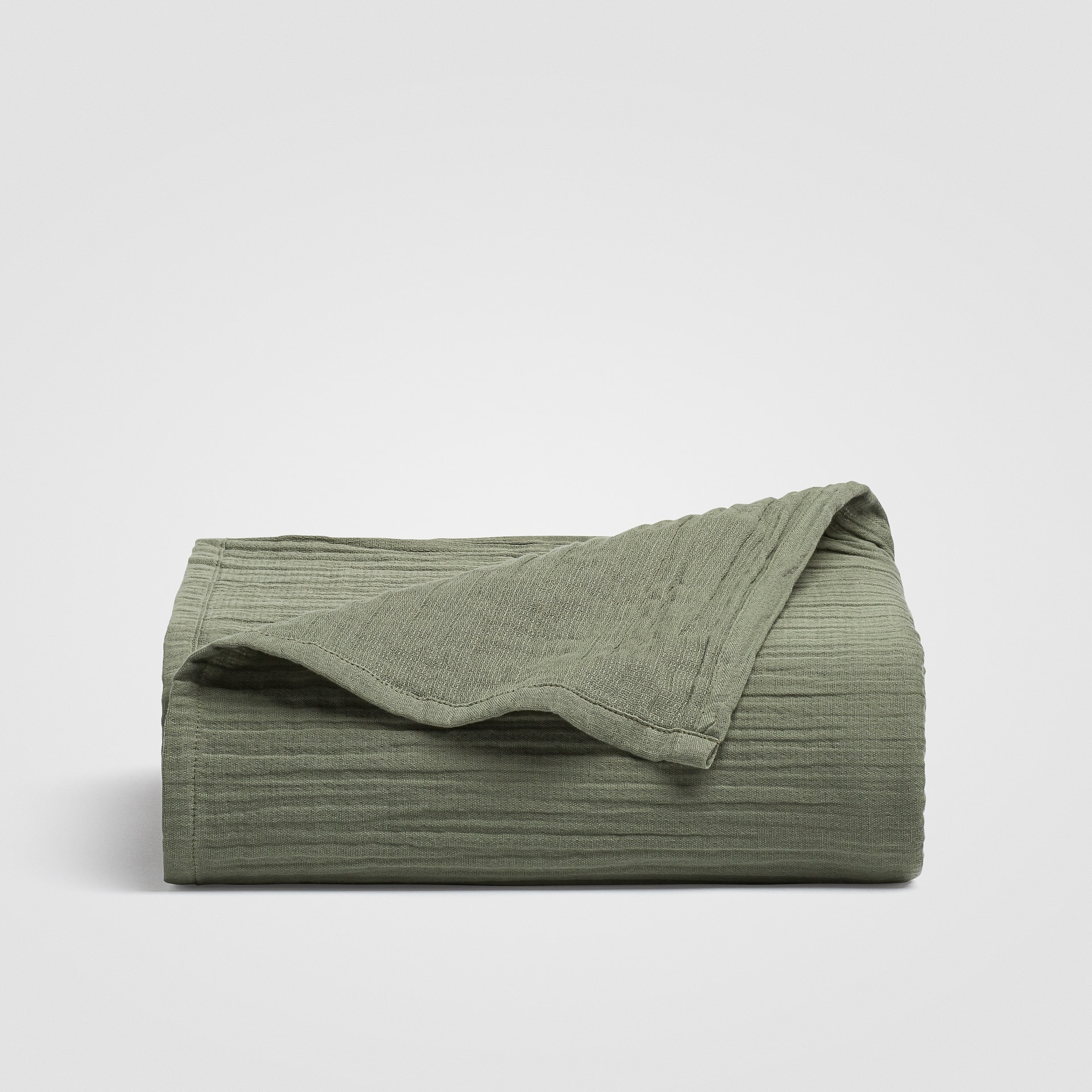 Folded sage green sheet stacked on a white background
