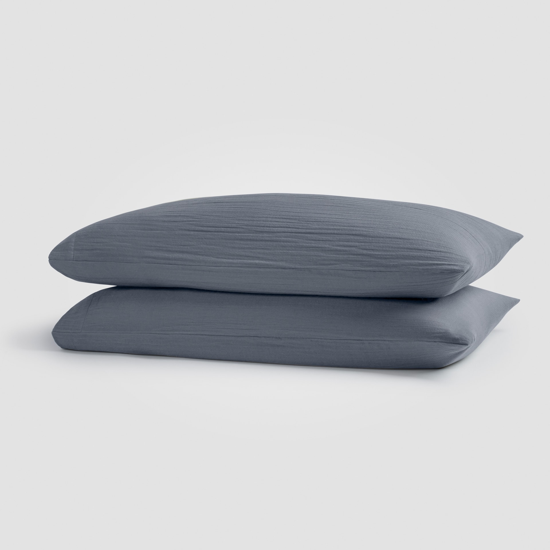 Set of dark blue pillowcases stacked neatly on a white surface