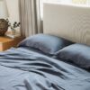 Bed with dark blue bedding and matching pillows in a warmly lit bedroom