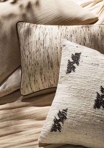 Decorative cream pillow with black embroidered accents on a faux fur blanket