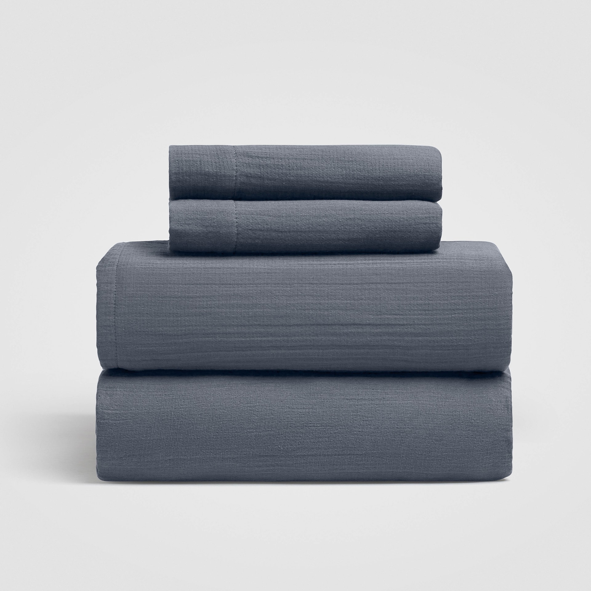 Stack of folded navy blue sheets on a white background