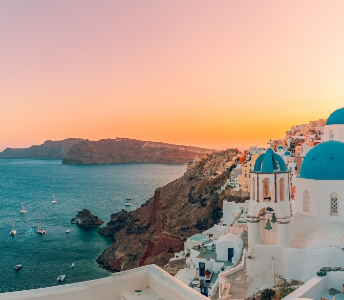 Sunset view of white buildings on a cliffside in Santorini, Greece, overlooking the ocean