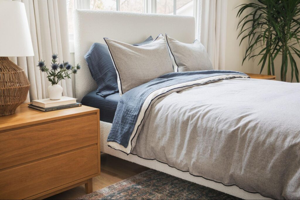 Bed with white and blue bedding next to a wood nightstand 