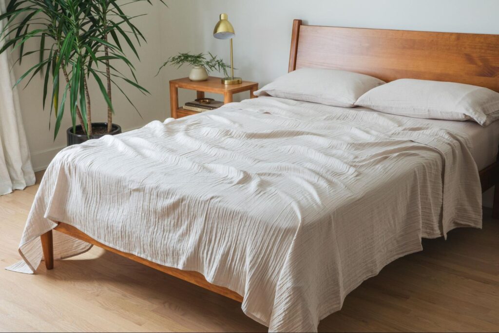 Corner of a bedroom with a bed, nightstand and palm plant