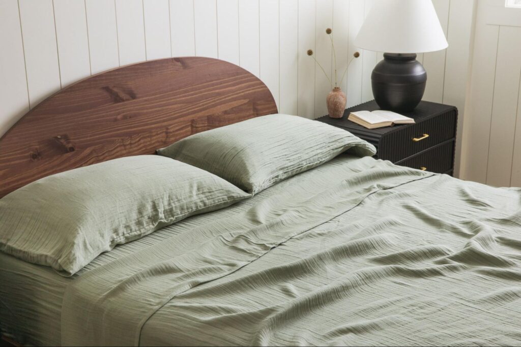 Bed with wooden headboard and sage green bedsheets