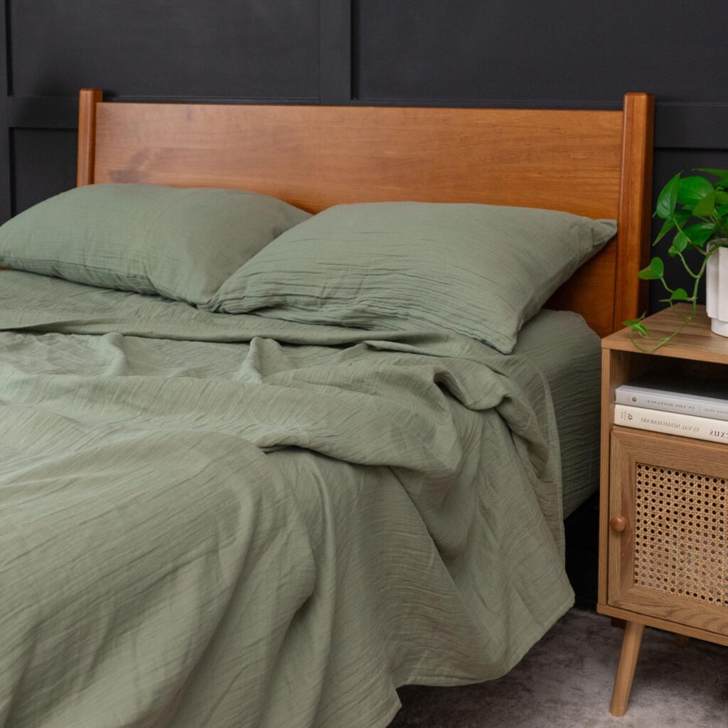Bed with wood headboard and sage green bedding