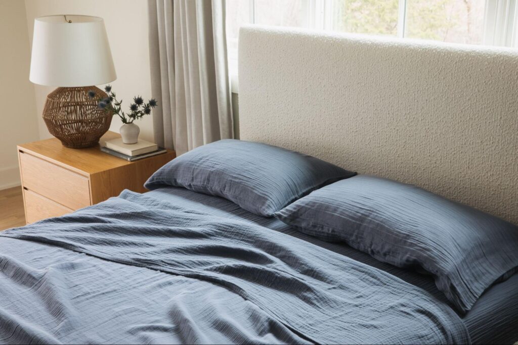 Bed with soft white headboard and blue bed sheets
