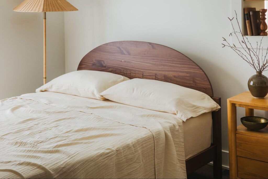 Bed with round wood headboard and cream bedsheets