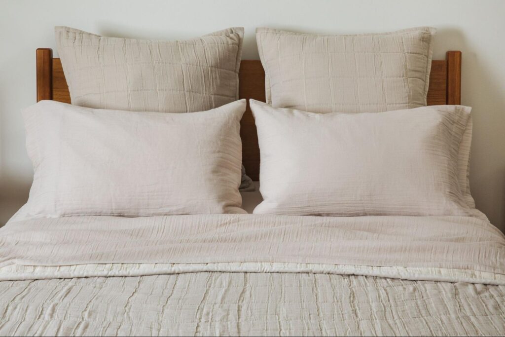 Front view of a bed with neutral bedding and wooden headboard 
