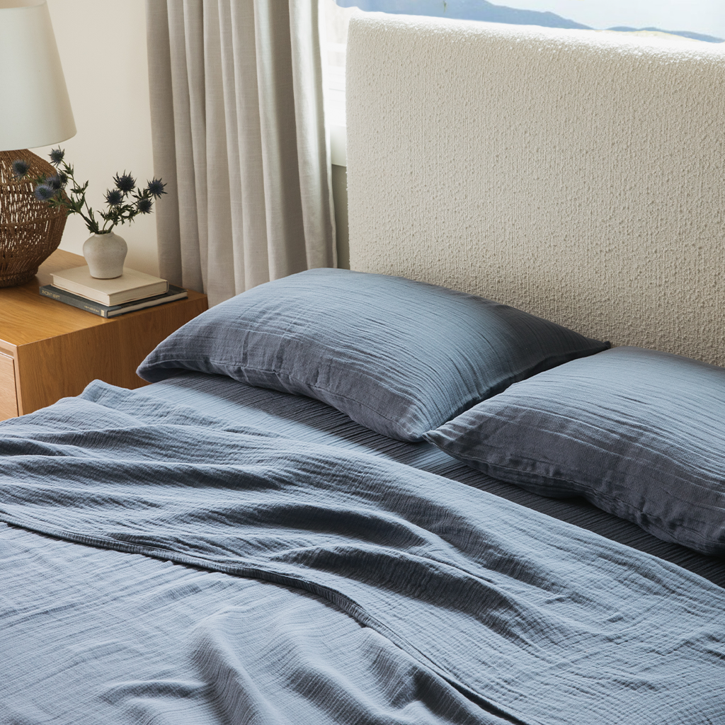 Bed with blue cotton bedding next to a wood side table